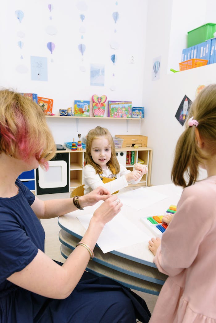 Children creating with modeling clay in a bright classroom setting with a teacher assisting.