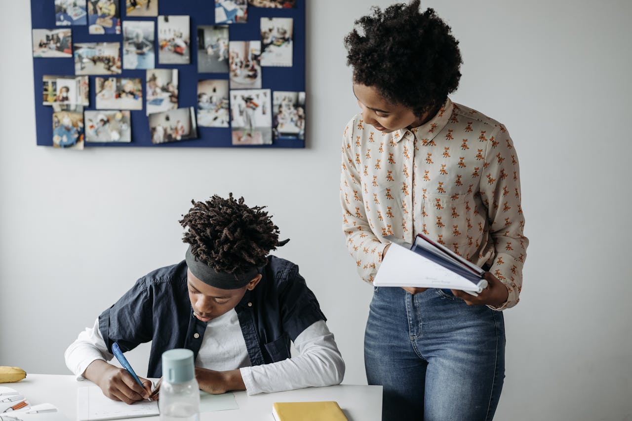 A teacher assists a student in a lively classroom setting, fostering interactive learning.